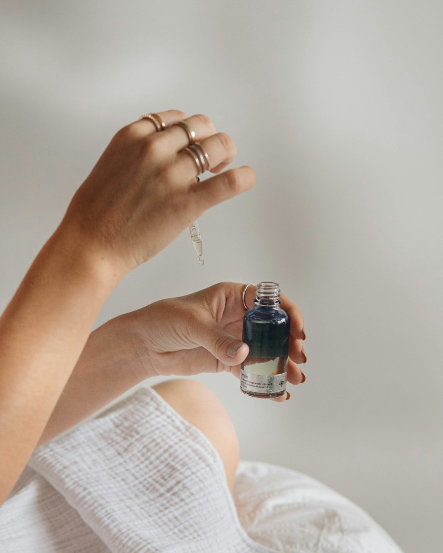 Hands drawing serum from a dark glass bottle