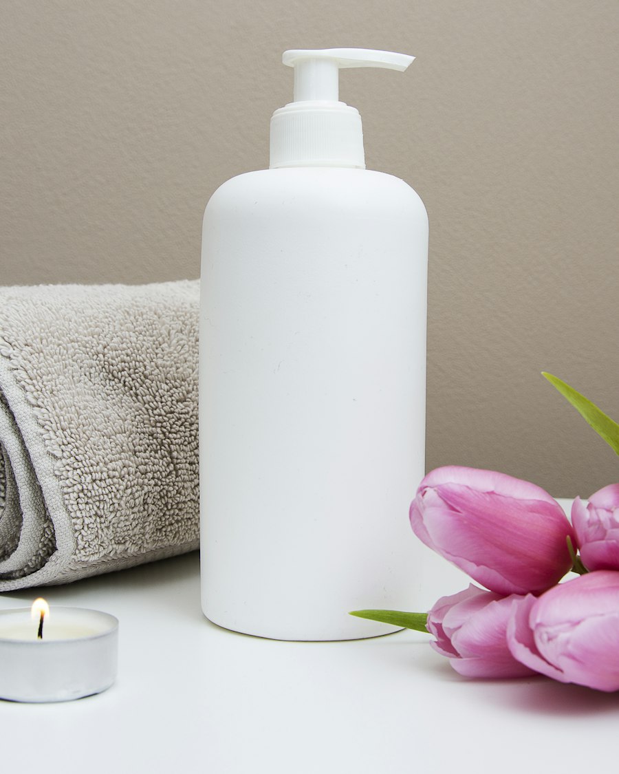 A rolled towel, a pump bottle and pink tulips in soft light